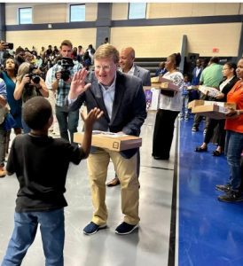 Gov. Tate Reeves hands out a free laptop to a student last week as Comcast celebrated a project that connected 1,700 homes to broadband internet service in the Bolton-Edwards area