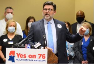 Tim Moore, President of the Mississippi Hospital Association (at podium), is joined by health care workers from across the state to advocate for getting Medicaid expansion on the 2022 ballot. Credit: Vickie D. King/Mississippi Today